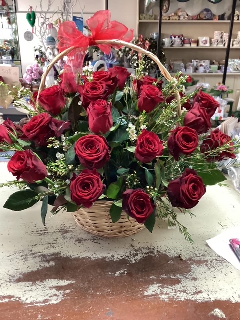 A basket arrangement of deep red roses with a red organza bow, made at the Bowbells Florist shop in Gloucester
